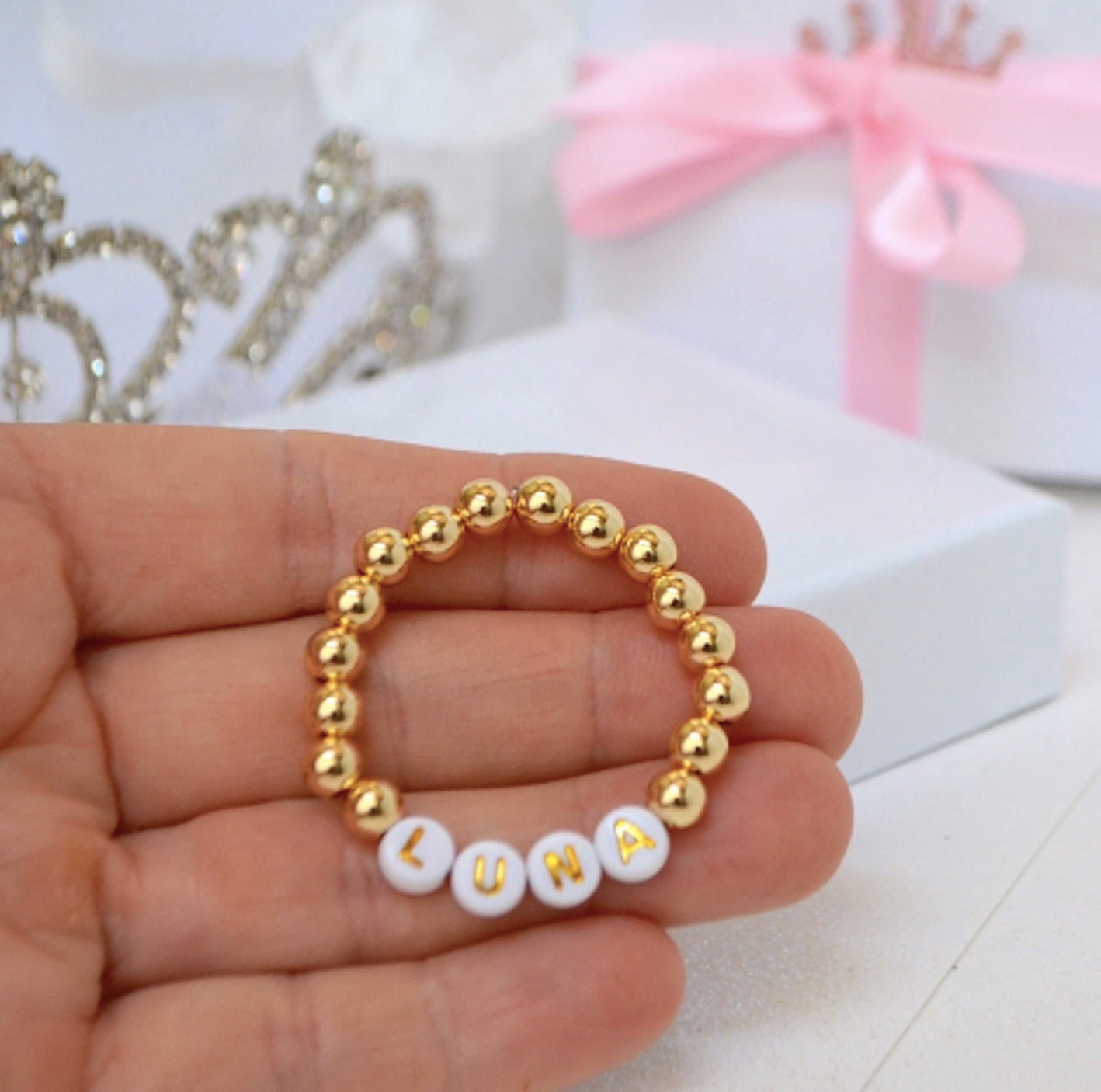 Personalized gold beaded baby name bracelet with custom lettering, perfect for baby gifts and special occasions like baptisms or birthdays.