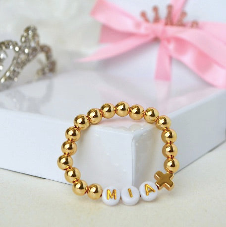A personalized 18K gold beaded baby bracelet featuring a small cross charm, beautifully designed as a baptism, christening, or baby shower gift for boys and girls