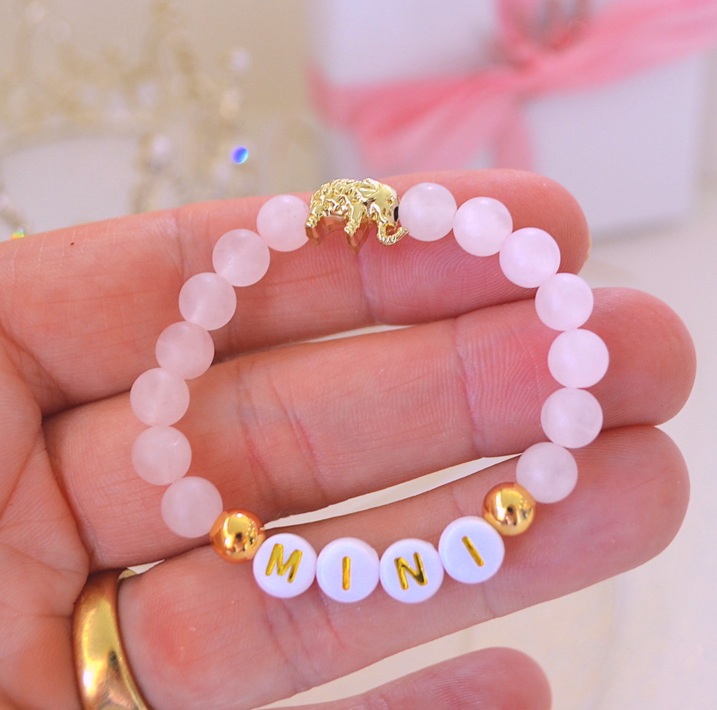 Personalized rose quartz gemstone bracelet for girls and toddlers, featuring a gold elephant charm and two gold accent beads, handmade gift jewelry